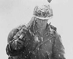 An American soldier holding a weapon while snow falls